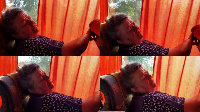 老年妇女在长途旅行中睡在窗户旁边的公共汽车上。