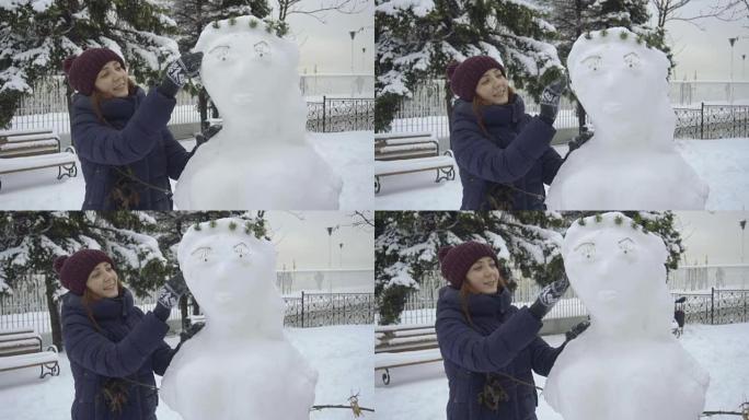 开朗的女人堆雪人，在户外享受冬天。