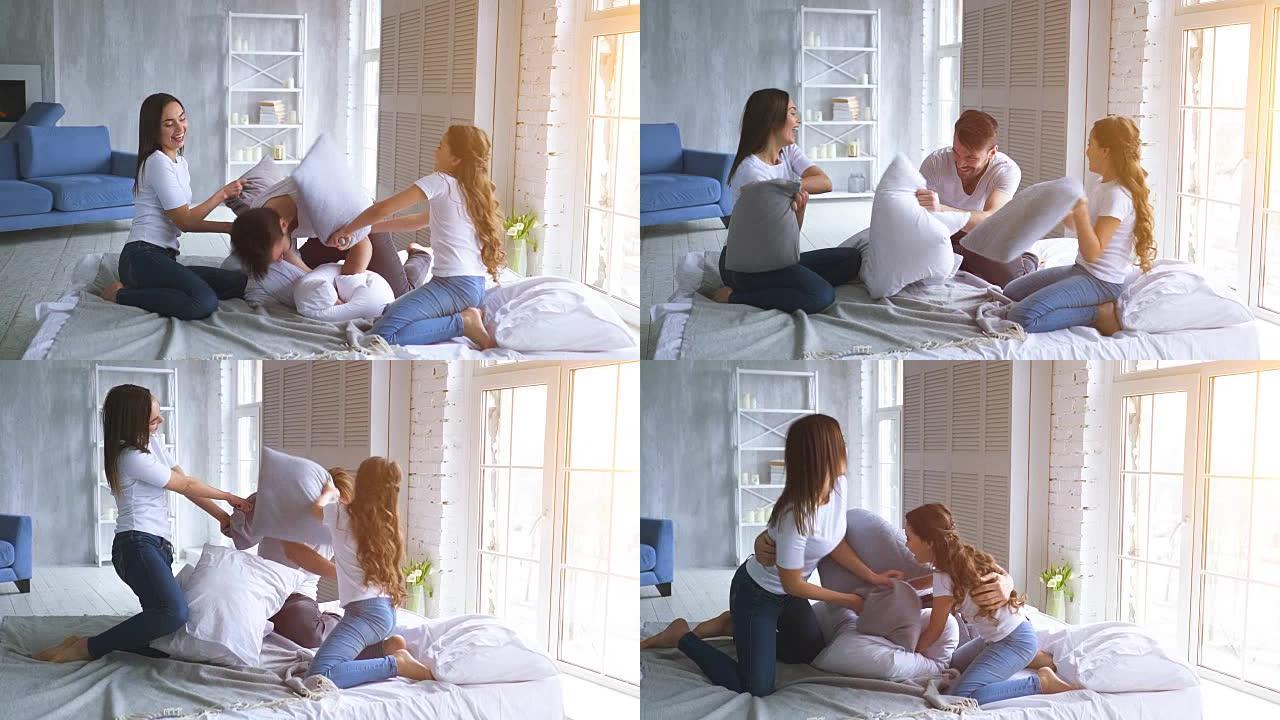 快乐的女儿和父母在床上用枕头打架。慢动作