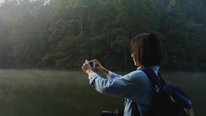 女人在美丽的大自然中使用智能手机拍照