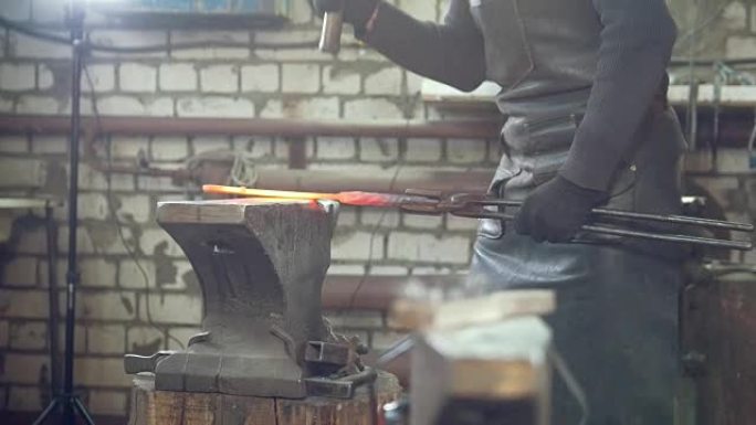 肌肉发达的铁匠用铁锤锻造钢刀