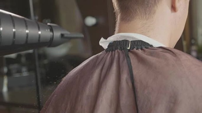 理发师完成理发，用刷子清洁顾客的脖子。
