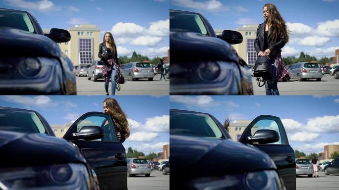 时尚的女孩在阳光明媚的夏日接近黑色汽车，打开门，坐在驾驶座上