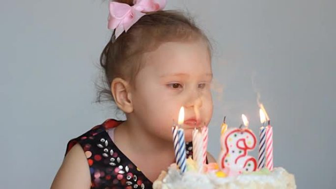 有趣的快乐孩子在派对上吹灭生日蛋糕上的蜡烛。可爱的小女孩。儿童假期的概念。3年