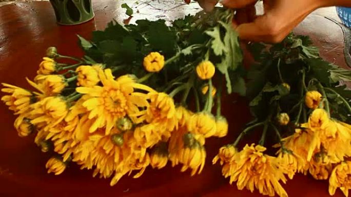 年轻女子花店的手的特写镜头在桌子上创作一束鲜花