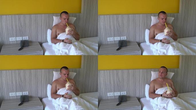 男子躺在床上，通过一根管子从年轻的椰子中喝椰奶