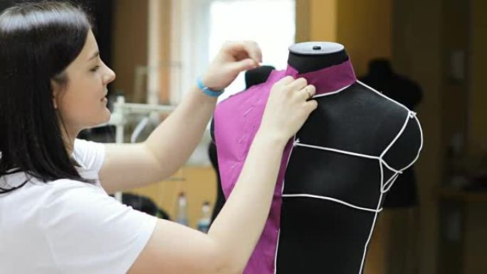 年轻女性时装设计师在工作室工作。服装设计师正在研究人体模型