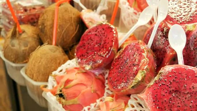 西班牙水果市场柜台上椰子旁边成熟多汁的红粉色火龙果