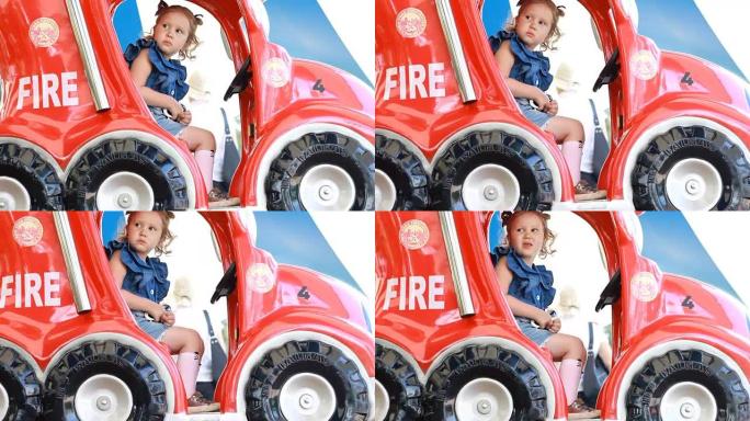 童女和在公园里骑消防车娱乐。儿童的吸引力。