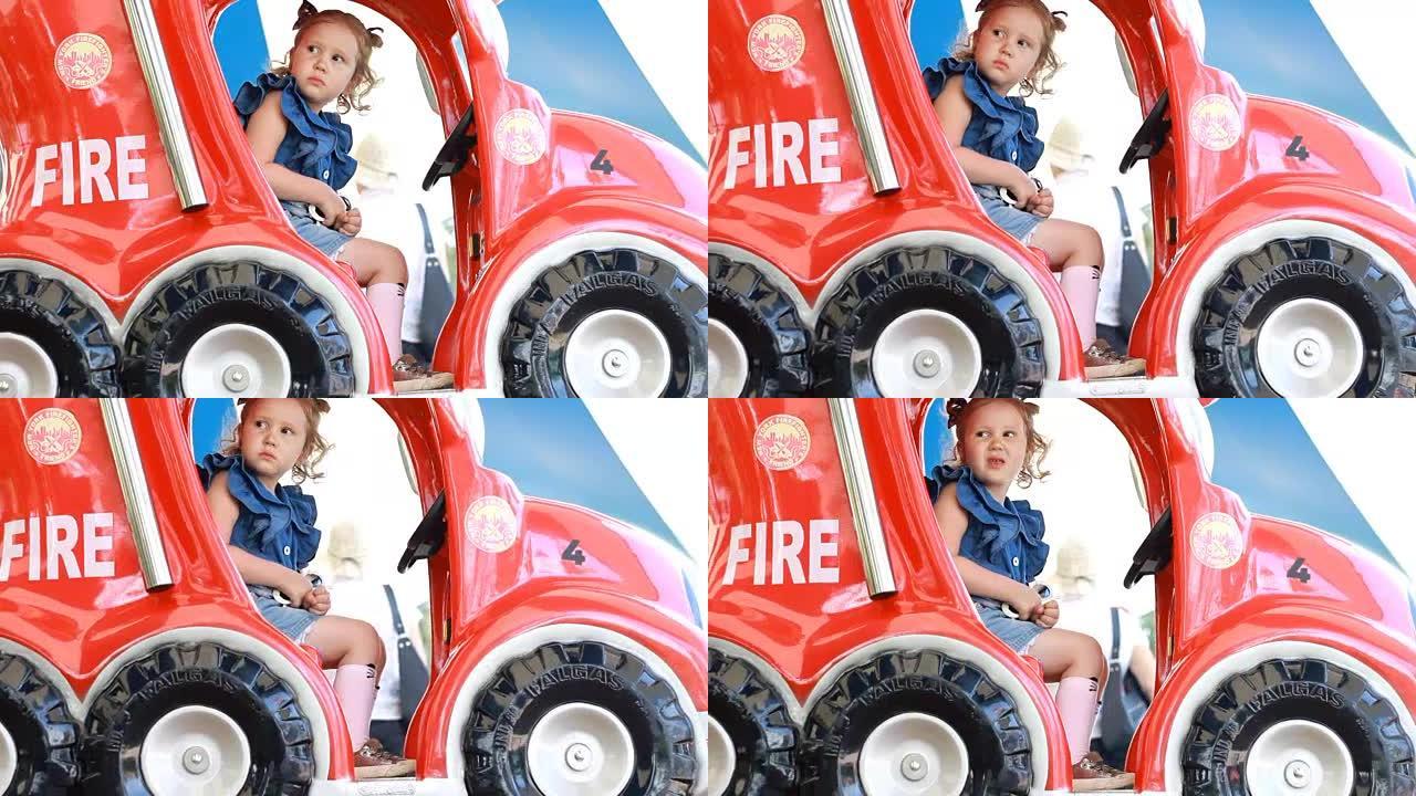童女和在公园里骑消防车娱乐。儿童的吸引力。