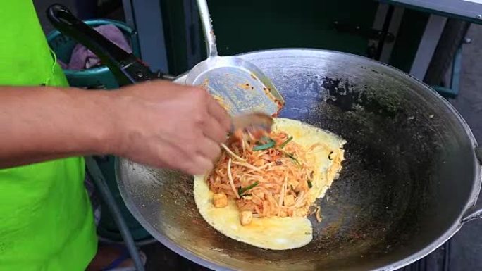 男子在泰国美食街市场煮泰国面条配鸡蛋