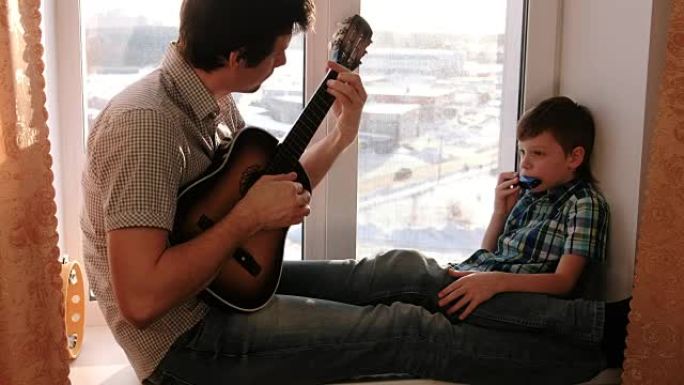 演奏乐器。爸爸在弹吉他，儿子坐在窗台上弹奏口风琴。