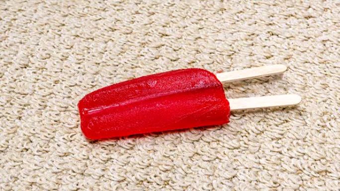 红色冰棍在地毯上融化