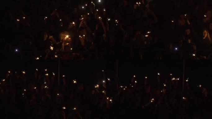 一群人举着燃烧的孟加拉灯。手里拿着明亮的节日烟火。黑暗中燃烧的火花。在庆祝圣诞节期间，手里拿着烟火的