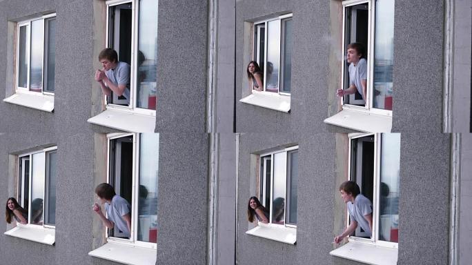 年轻人透过窗户与邻居交谈。年轻人抽烟，从窗户与邻居交谈