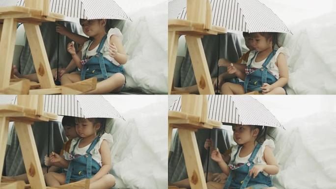 泰国可爱女婴在雨伞下在哥哥旁边跳舞时正在吃糖果