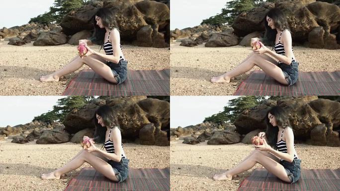 一个女孩坐在海边的海滩上切了一个火龙果火龙果