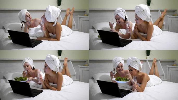 女友拿着香槟拿着浴巾坐在笔记本电脑上的互联网上