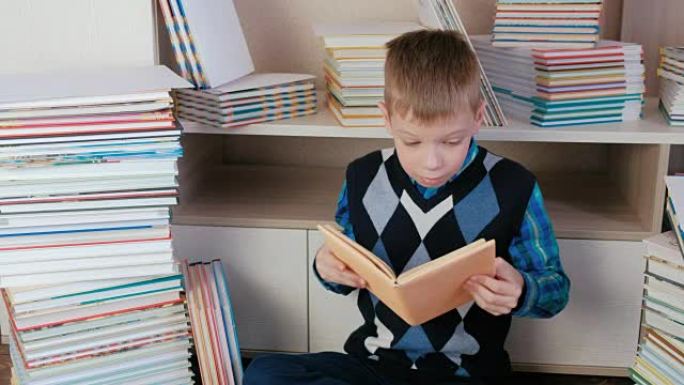 七岁的男孩把书从书堆里拿出来，坐在书里看书。