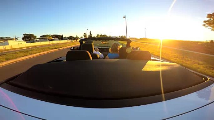 白人夫妇在日落时驾驶出租敞篷车