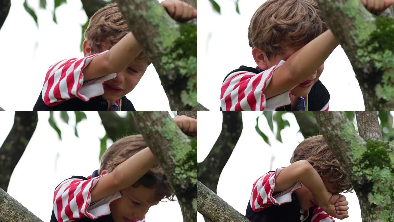 哭泣的孩子在哭泣和哭泣时擦着眼睛。4k剪辑的小男孩在树顶上挣扎着哭泣