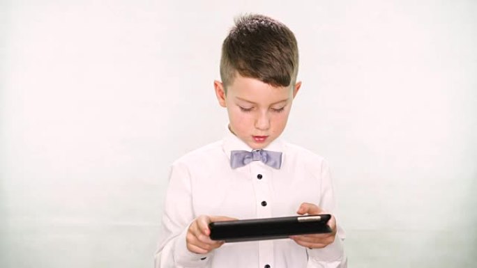 男婴竖起大拇指，在白色背景上玩平板电脑或智能手机