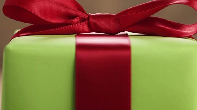木桌上有经典红丝带蝴蝶结的绿纸礼品盒