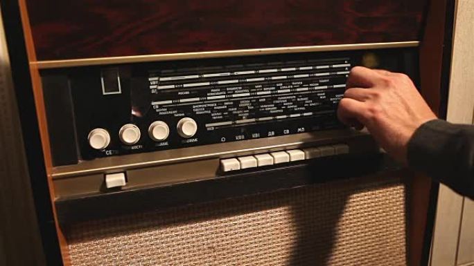 复古收音机，男人改变旧收音机接收器上的频率，旧接收器上的频率改变