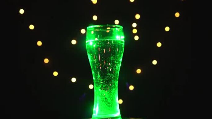 浅绿色灯光下的一杯水正在旋转。绿色鸡尾酒。酒吧概念
