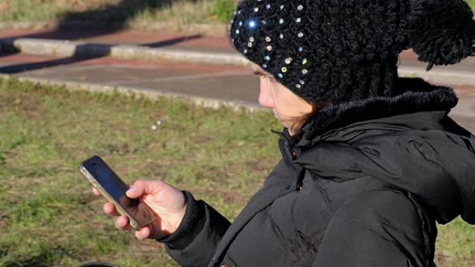 严肃的女人坐在公园的长凳上看着她的智能手机