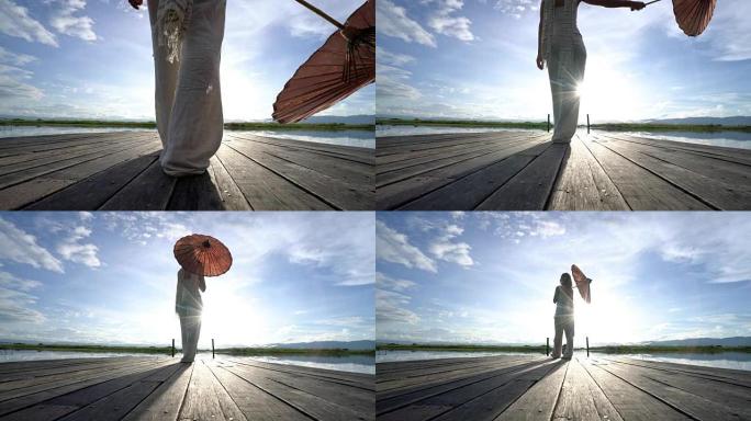 缅甸因勒湖木码头上女子手持红色传统伞行走的低角度视角 -- 旅游概念