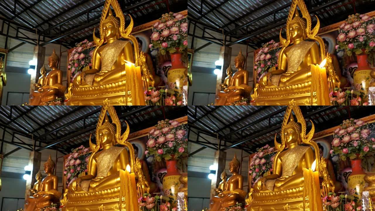蜡烛在寺庙金佛雕像的背景上燃烧。芭堤雅。泰国