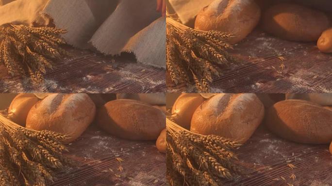 手工制作的美味面包躺在木桌上的粗麻布上，上面有面粉，小麦和麦穗