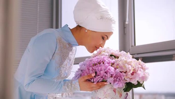 穿着蓝色婚纱的穆斯林新娘为尼迦 (nikah) 闻到鲜花