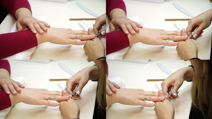 女人在修指甲之前先修剪和清洁指甲。用剪刀修指甲