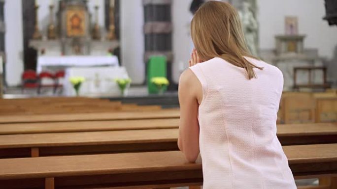 年轻虔诚的宗教妇女在天主教堂祈祷。欧洲大教堂的忠实天主教徒