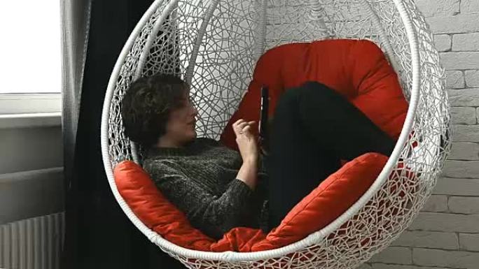 一个女人躺在椅子上，手里拿着手机