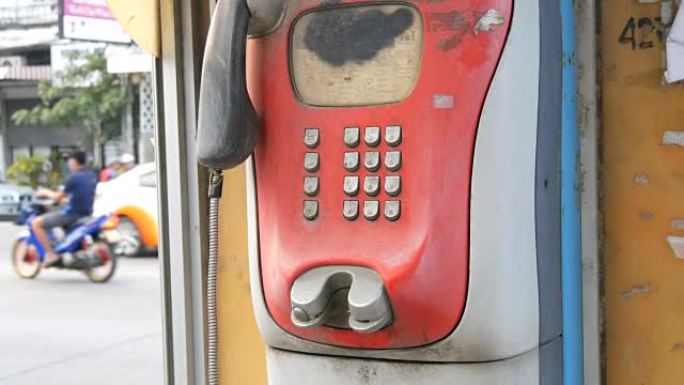 城市街道上破旧的红色电话机。电话亭里的老式电话