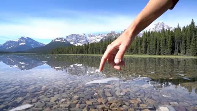 手指触摸加拿大山湖表面-4K