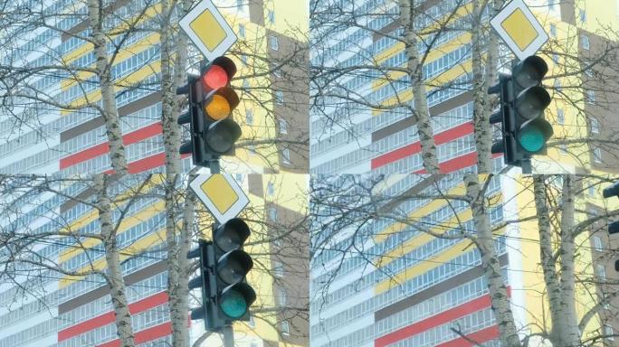 交通灯在多层建筑的背景上从红色切换到黄色和绿色。