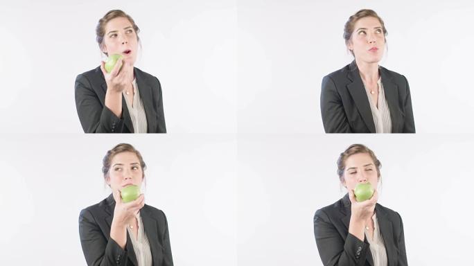女人在白色工作室背景上吃青苹果