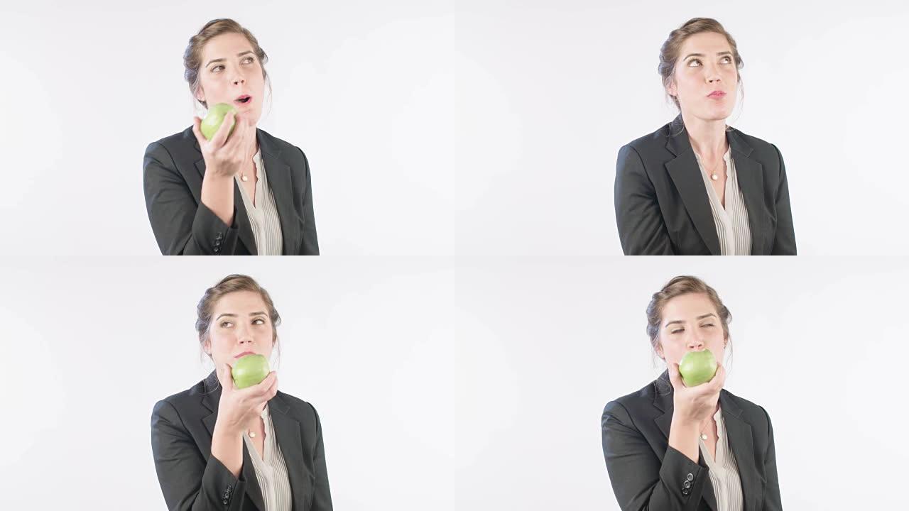 女人在白色工作室背景上吃青苹果
