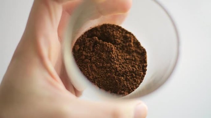 专业咖啡师展示新鲜研磨的高品质咖啡及其烘焙程度。一个男人的手旋转装有咖啡粉的玻璃烧杯
