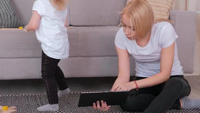 妈妈用平板电脑向女儿展示了一些东西，但她想玩木块。