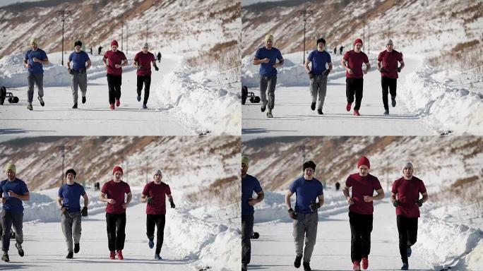 在寒冷的冬日里，四名运动员穿着运动服和帽子在山区附近的训练中心的雪道上慢跑。