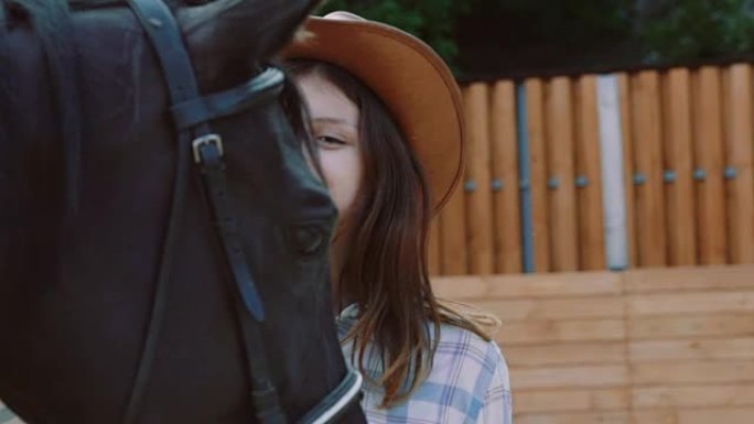 漂亮的年轻女孩走向友好的马，爱抚它的鼻子。慢慢地