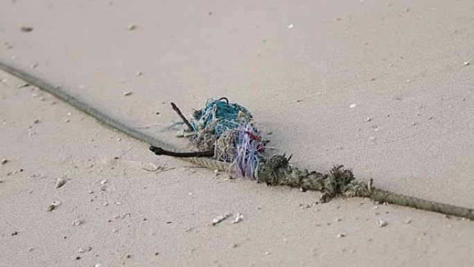 由不同的彩色零件和螺纹制成的旧绳子躺在沙子上。泰国普吉岛拉瓦海滩