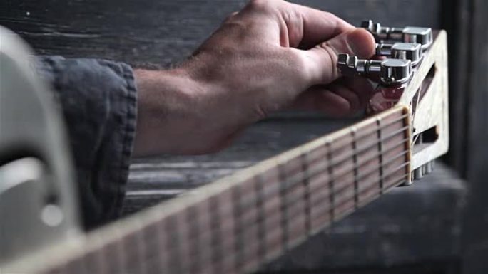 closeup of hand tuning guitar