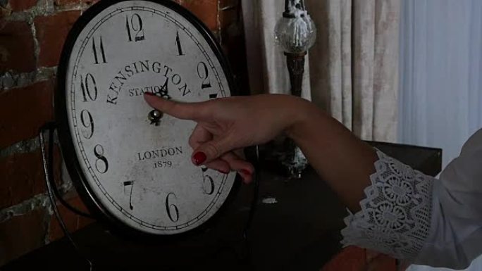 女人和时钟。女性的手在时钟的表盘上。