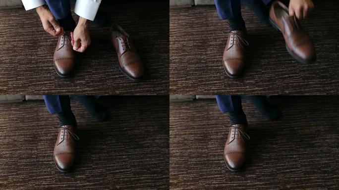 男人在棕色皮鞋上系鞋带。